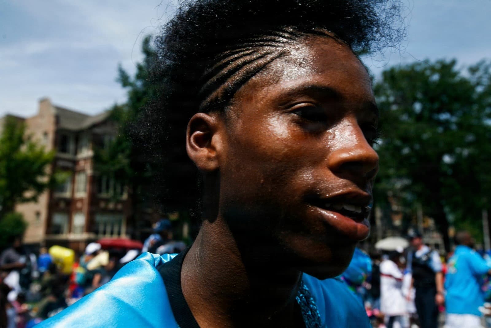 Sweaty young person with cornrows in blue costume at Bud Billiken Parade